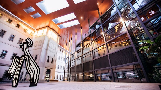 A modern building with large glass windows and a geometric ceiling design. - Casa de huéspedes asturiana (Madrid)