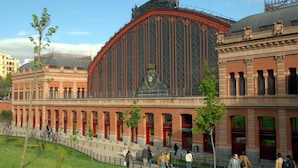 A historic building with a large central clock, arched windows, and a red facade. - Casa de huéspedes asturiana (Madrid)