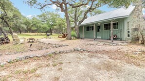 A rustic cabin with a porch, surrounded by trees and a gravel path. - Rosemary Cabin I Couples, Stargazing, Hill Country (Wimberley)