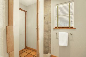 Une salle de bain avec une douche, un porte-serviettes et une fenêtre avec des stores.