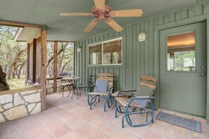 Un patio couvert doté d’un ventilateur de plafond, de murs en pierre et offrant une vue sur l’extérieur.