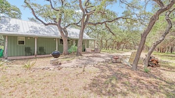 A rustic cabin with a covered porch, a barbecue grill, and outdoor seating.