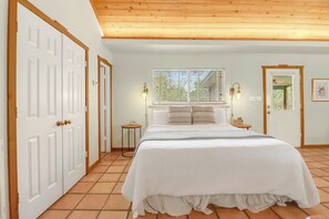 Une chambre à coucher avec un lit, deux lampes de chevet, une fenêtre avec des stores et une porte.