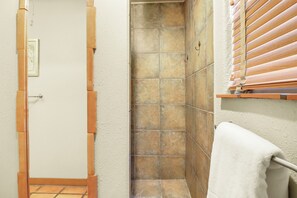 A bathroom with a shower, a towel rack, and a door.