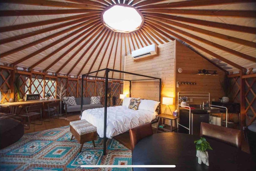 A yurt with a four-poster bed, a desk, and a seating area.