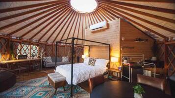 A yurt with a four-poster bed, a desk, and a seating area.