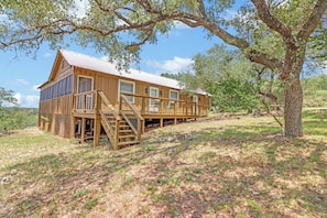 A wooden cabin with a deck, stairs, and a large tree in the background. - Prickly Pear Cabin I Stargazing, Couples (Wimberley)