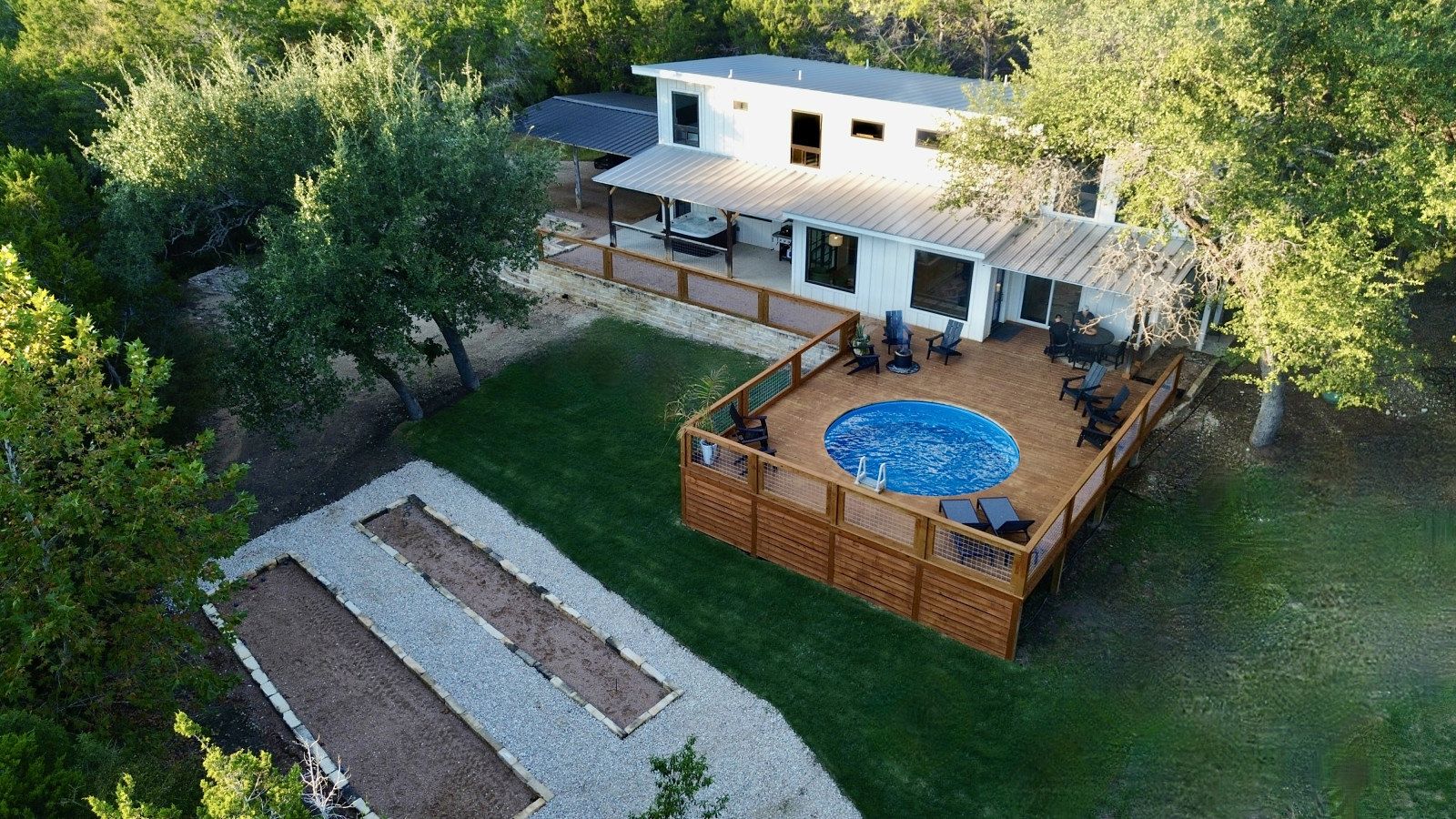 Ett modernt hus med en stor terrass, en swimmingpool och en välskött gräsmatta.