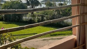 A balcony with a view of a landscaped area, including grass, trees, and a distant hill. - Beautifully furnished flats with sea view (Lecci)