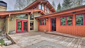 Ein zweistöckiges Haus mit einer Holzdiele, großen Fenstern und einer roter Tür.