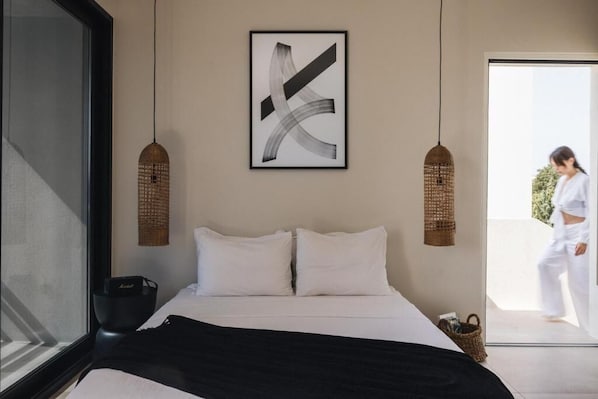 Un dormitorio moderno con una cama grande, dos cestos colgantes y una obra de arte abstracta enmarcada en la pared.