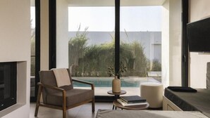 A modern living room with a large window, a pool view, a flat-screen TV, and a comfortable seating area. - Hooga (Preveza)