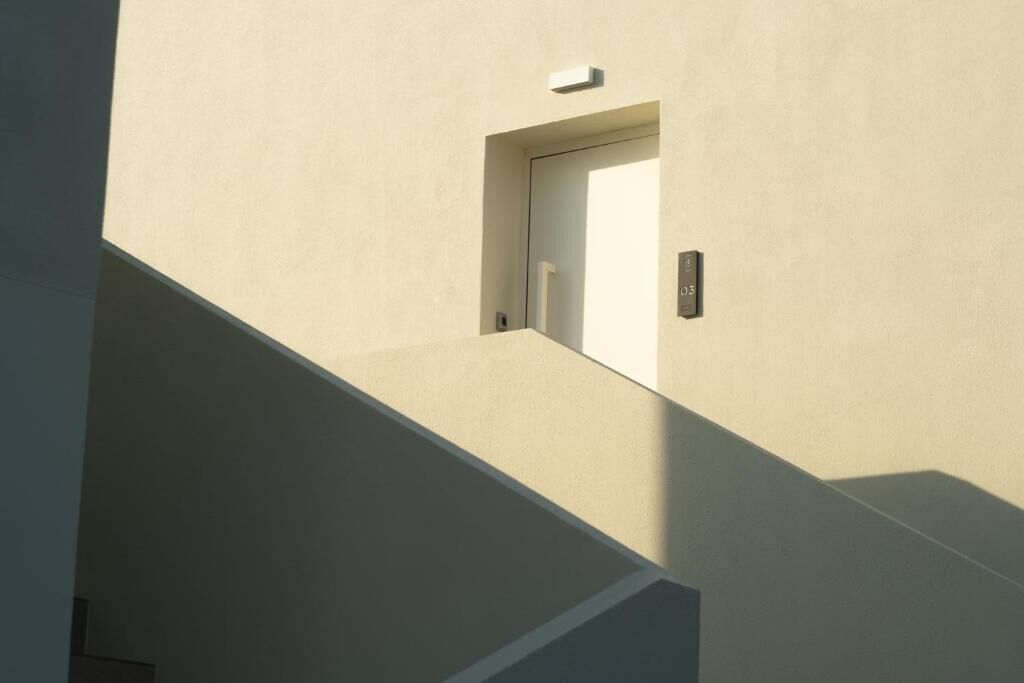 Un escalier moderne au design minimaliste, une petite fenêtre et une porte avec un interrupteur.