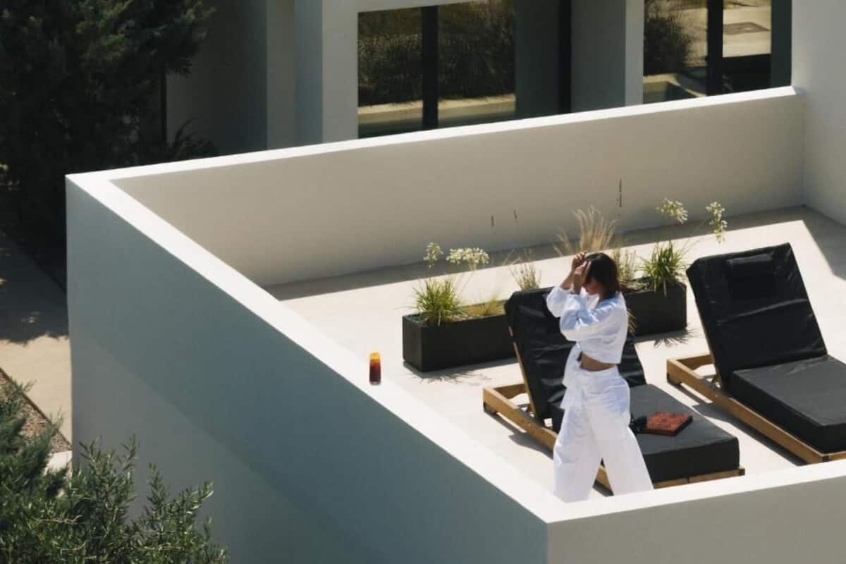 A rooftop terrace with lounge chairs, potted plants, and a person taking a photo.