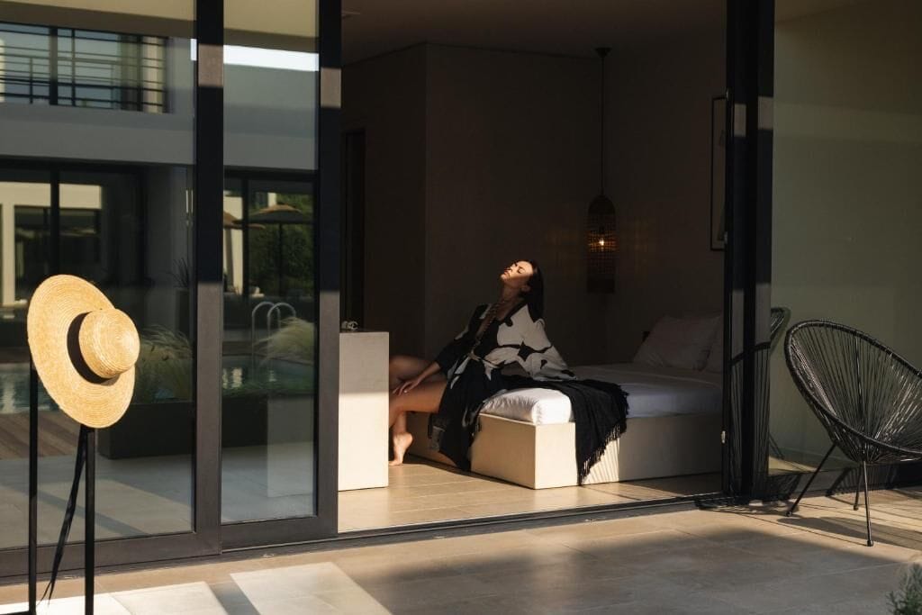 Un interior moderno con una cama, un sillón y un ventanal grande.