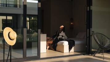 Un interior moderno con una cama, un sillón y un ventanal grande.