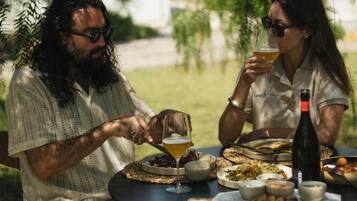 Two people dining outdoors at a round table with various dishes and drinks.
