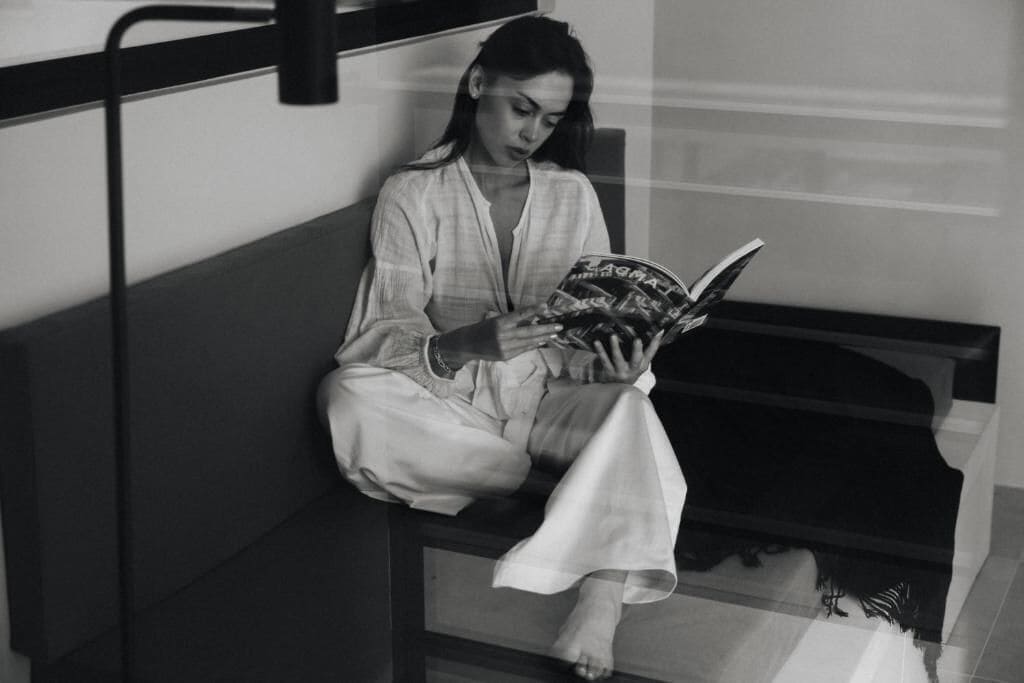 A person sitting on a bench reading a book.