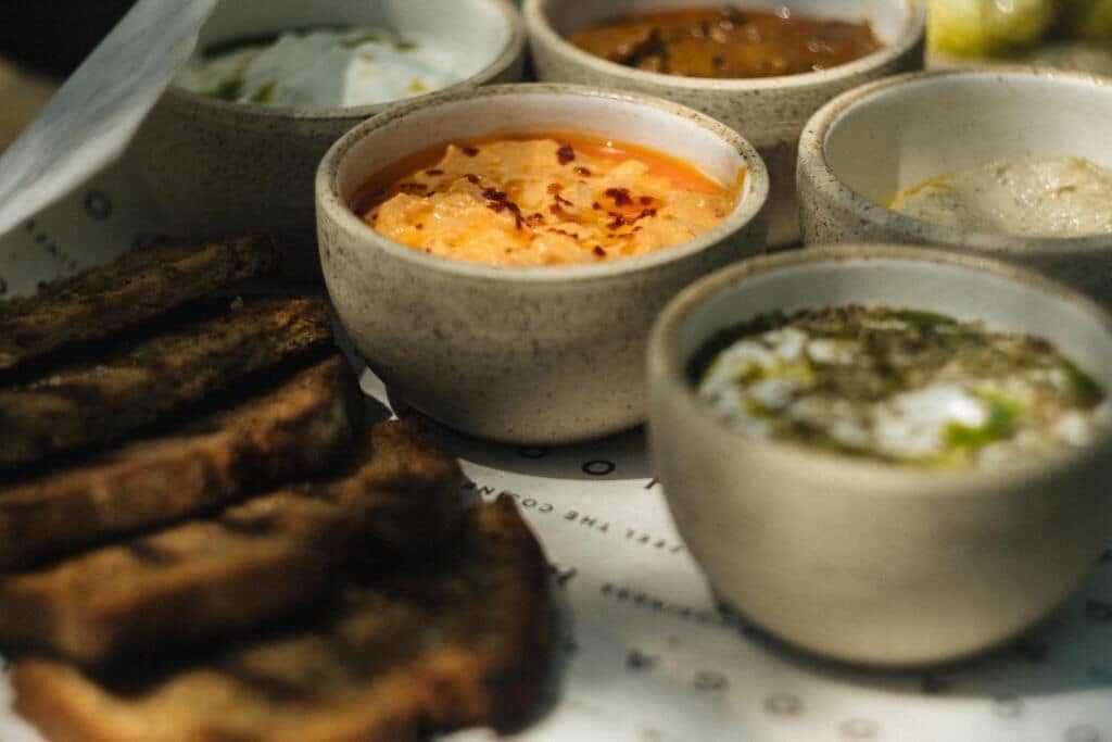 Una bandeja con diferentes salsas para mojar y carne a la parrilla.