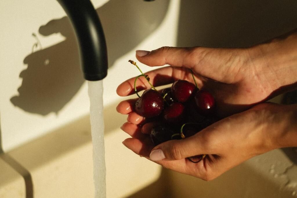Hands holding cherries under a running tap.