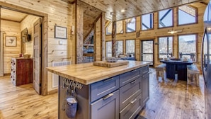 A wooden interior with a kitchen island, built-in cabinets, and large windows offering views.