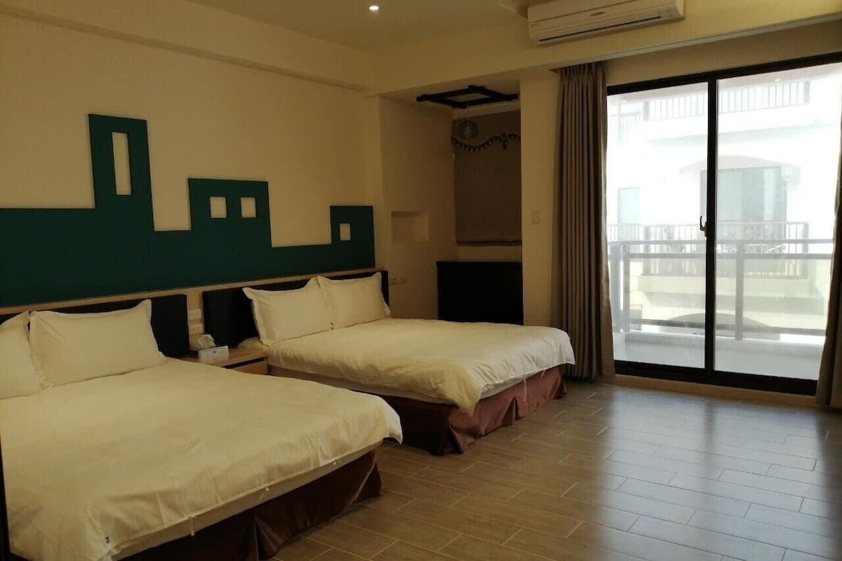 Quarto de hotel com duas camas, uma janela grande com vista e um aparelho de ar condicionado.