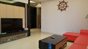 Una sala de estar moderna con un televisor de pantalla plana, una mesa de centro, un sofá rojo y un adorno con forma de timón en la pared.