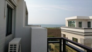 Un balcón con vista al mar y edificios cercanos.