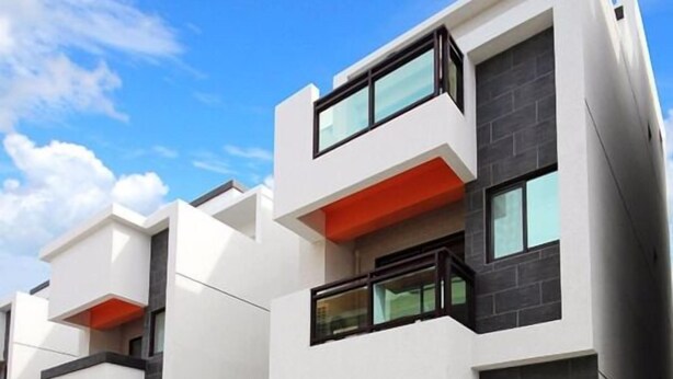Un edificio residencial moderno de varios pisos con balcones, ventanas amplias y un diseño arquitectónico limpio.