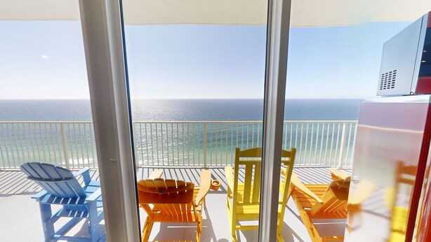 Ein Balkon mit Blick auf das Meer, ausgestattet mit blauen und gelben Stühlen sowie einem Tisch.