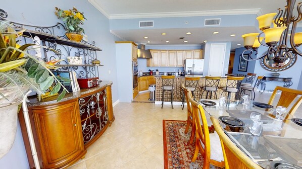 Una cocina amplia con una isla central, armarios de madera y un comedor con mesa y sillas de vidrio.