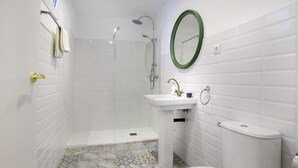 A bathroom with white tiled walls, a shower, a sink with a mirror, and a toilet. - Hotelito Boutique Camp Nou 2 (Hospitalet de Llobregat, Barcelona)