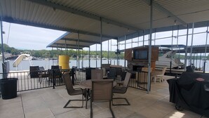 A covered outdoor seating area with tables and chairs, overlooking a body of water.