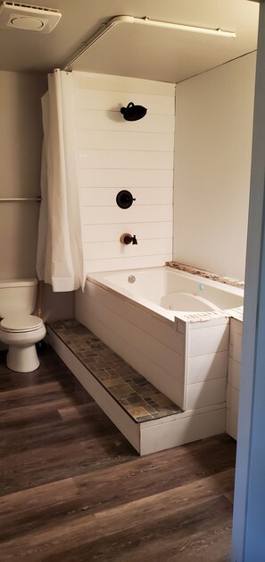 Een bad/douchecombinatie, een bubbelbad, handdoeken