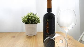 A bottle of wine, a wine glass, and a potted plant on a wooden table.