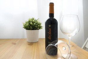 Una botella de vino, una copa de vino y una planta en maceta sobre una mesa de madera.