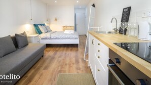A compact hotel room with a bed, a sofa, a kitchenette, and a small bathroom. - Hotelito Boutique Mercat 6 (Hospitalet de Llobregat, Barcelona.)