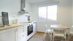 A modern kitchen with white cabinets, a gas stove, a built-in oven, and a window with frosted glass. - Hotelito Boutique Mercat 6 (Hospitalet de Llobregat, Barcelona.)