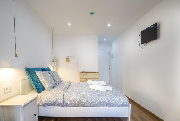 A modern bedroom with a bed, bedside tables, a TV, and a wardrobe.