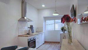 Cozinha compacta com fogão, pia e uma pequena área de refeições com mesa e cadeiras.