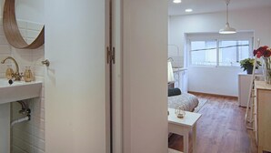 Quarto moderno com cama, mesa de cabeceira e janela com vista.