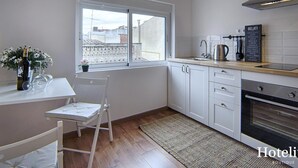 A modern kitchen with white cabinets, a window, a sink, and a coffee maker.
