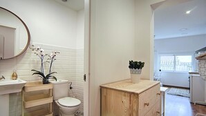 A modern bathroom with a white sink, toilet, and vanity with a wooden cabinet.