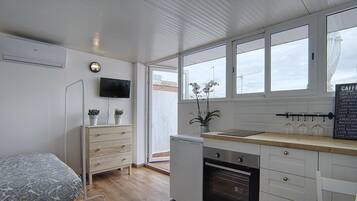 Una kitchenette compacta con horno integrado, un lavamanos pequeño y ventana con vistas a un balcón.