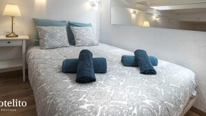 Ein Hotelzimmer mit einem großen Bett, einem Nachttisch mit Lampe, einem Spiegel und einer Deckenleuchte.