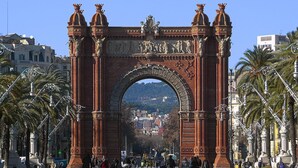 A large red archway with statues and reliefs, surrounded by palm trees and a cityscape in the background. - Hotelito Boutique Cinca 3 (Hospitalet de Llobregat, Barcelona)