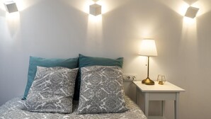 A bedroom with a bed, two patterned pillows, a bedside lamp, and wall-mounted lights. - Hotelito Boutique Cinca 3 (Hospitalet de Llobregat, Barcelona)