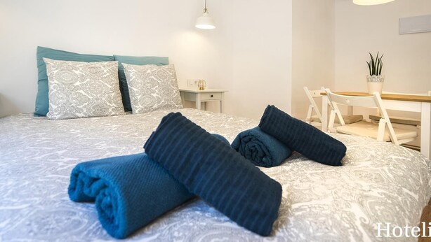 A hotel room with a neatly made bed, a desk with a chair, and a hanging light fixture. - Hotelito Boutique Cinca 4 (Hospitalet de Llobregat, Barcelona)