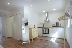 Een moderne keuken met witte kasten, een roestvrijstalen afzuigkap en een houten aanrecht.