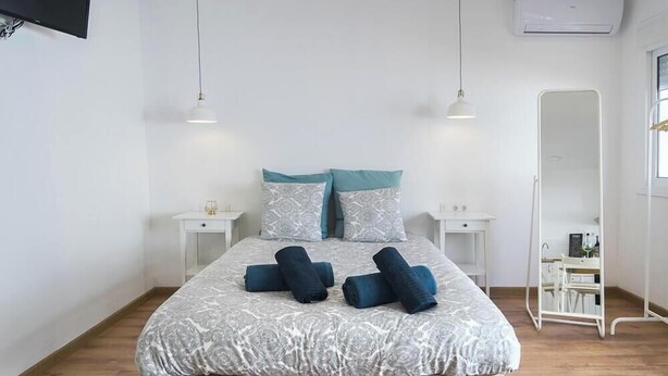 Un dormitorio moderno con una cama grande, dos mesitas de noche, un espejo y un equipo de aire acondicionado.